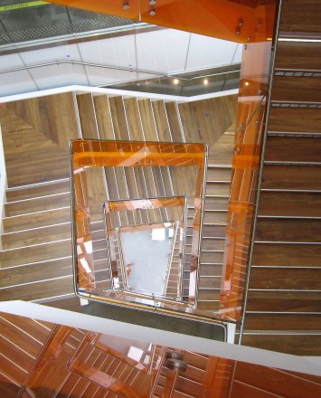 Angled view at University of California Berkley, Helios building, CA, Optik guardrail with orange tinted glass and stainless steel handrail