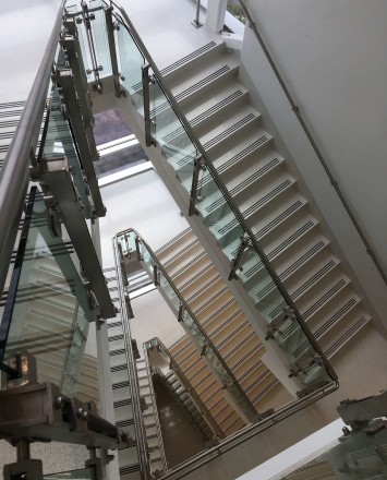 View down a stairwell of Inox guardrail with clear glass infill.