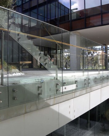 Outdoors side angled view at University of California San Diego, CA, Optik guardrail with clear glass and wood handrail