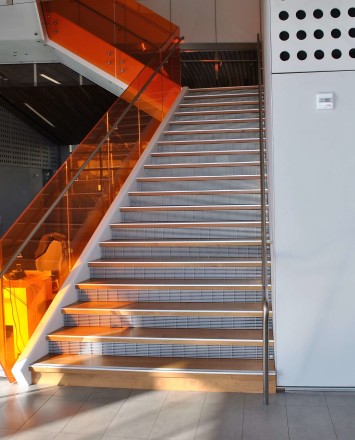 Angled view at University of California Berkley, Helios building, CA, Optik guardrail with orange tinted glass and stainless steel handrail