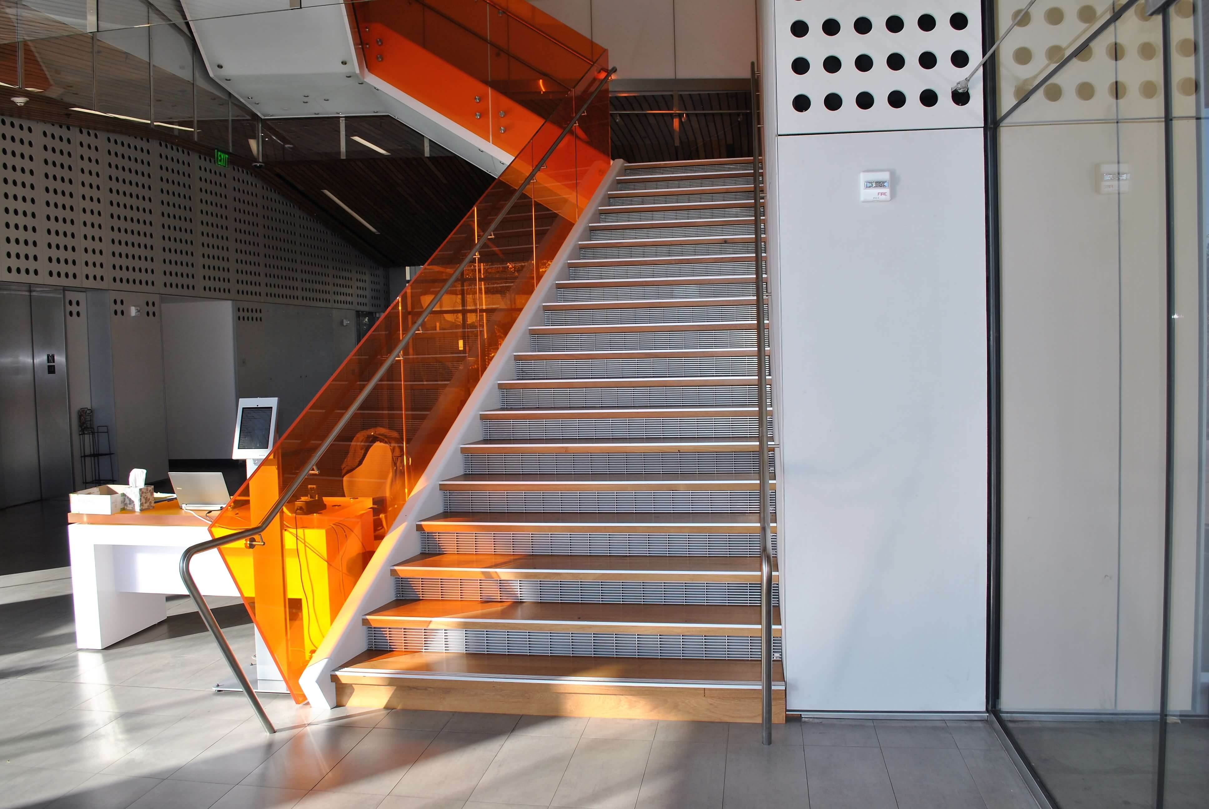 Angled view at University of California Berkley, Helios building, CA, Optik guardrail with orange tinted glass and stainless steel handrail