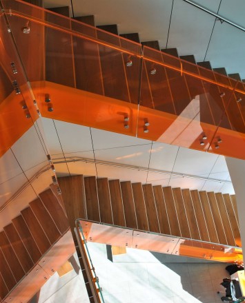Angled view at University of California Berkley, Helios building, CA, Optik guardrail with orange tinted glass and stainless steel handrail