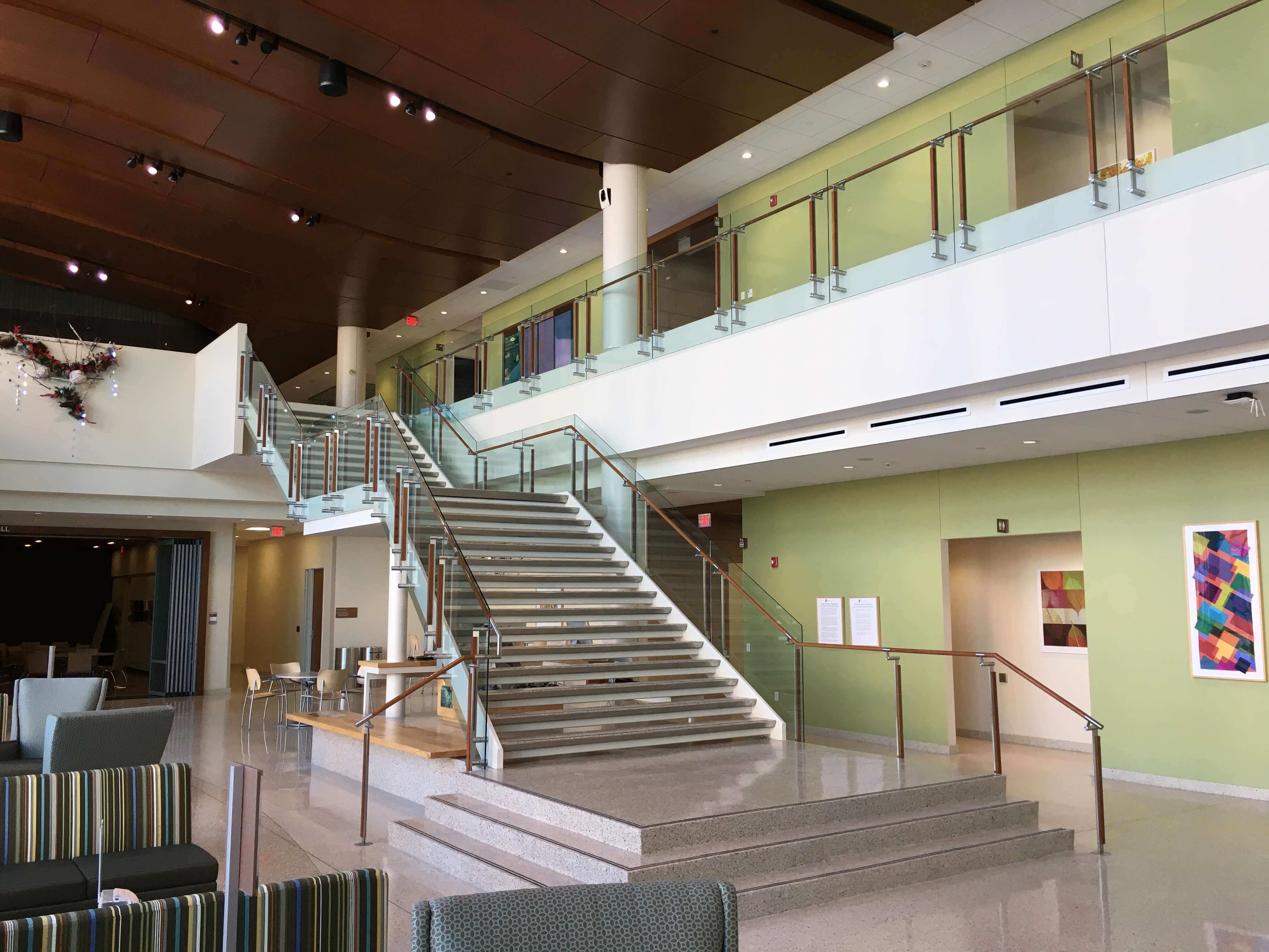 Atrium stair at University of Wisconsin School of Nursing, Kubit glass railing with wood top rail and posts.