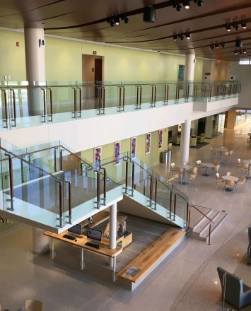 Atrium stair at University of Wisconsin School of Nursing, Kubit glass railing with wood top rail and posts.