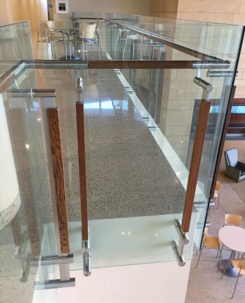 Atrium stair at University of Wisconsin School of Nursing, Kubit glass railing with wood top rail and posts.