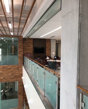Circum guardrail installation with wood handrail and frosted glass infill at Texas State University, TX.