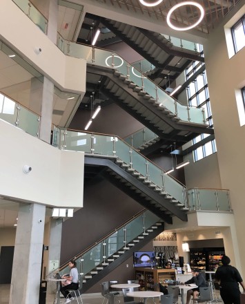 Circum guardrail installation with wood handrail and frosted glass infill at Texas State University, TX.