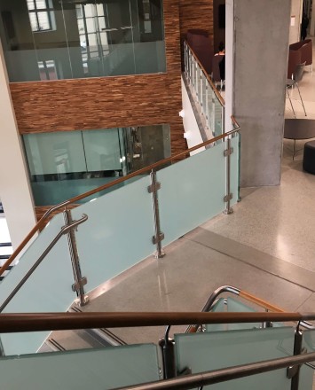 Circum guardrail installation with wood handrail and frosted glass infill at Texas State University, TX.