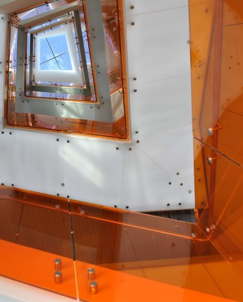 Skyward view of spiraling Optik guardrail with orange colored glass infill at UC Berkley's Helios Building, CA.