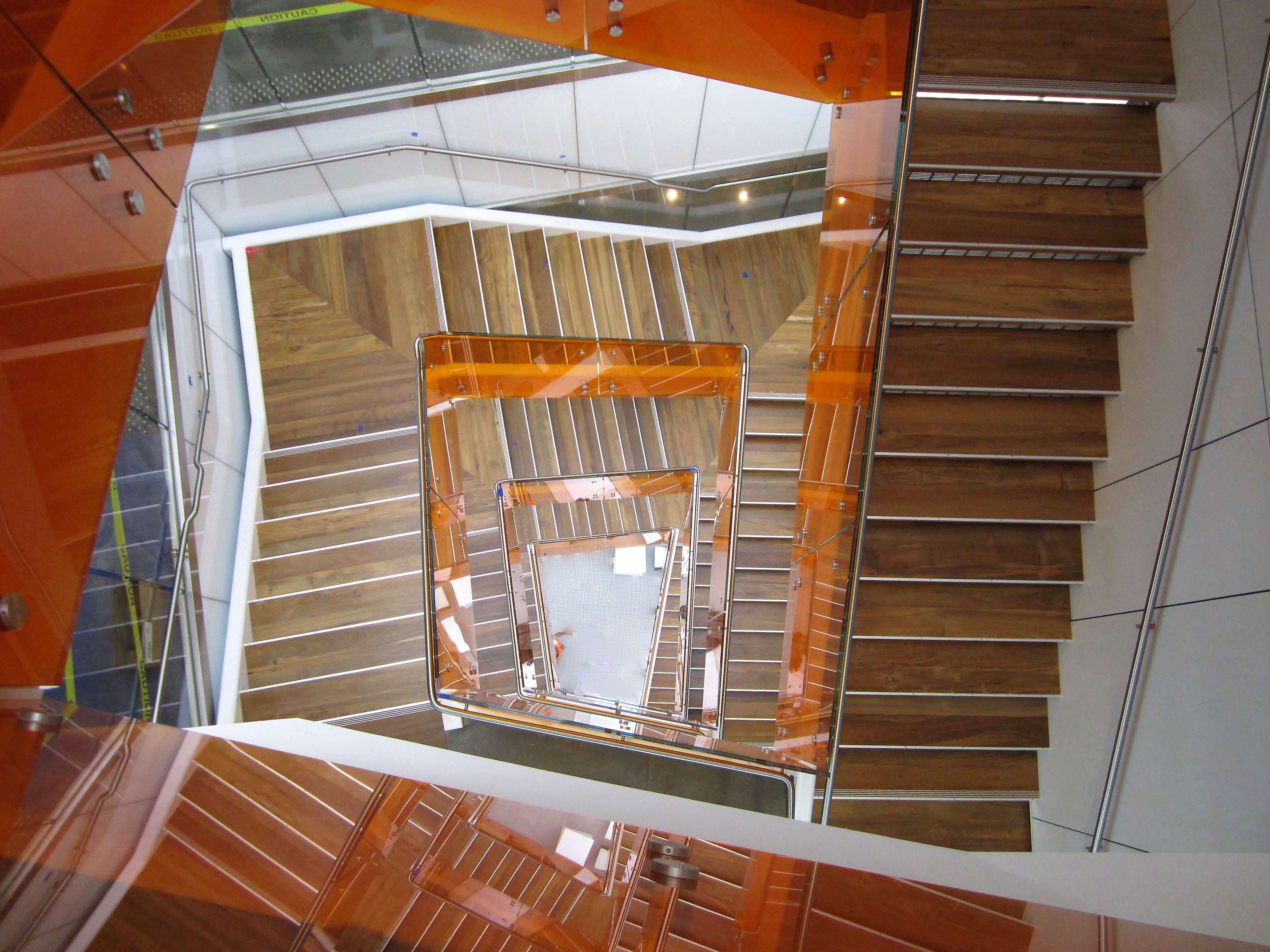 View of stair well with Optik guardrail and orange colored glass infill at UC Berkley's Helios Building, CA.
