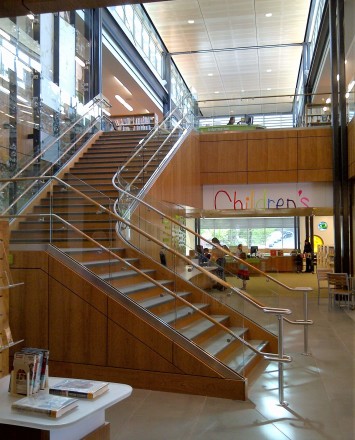 Upward view of open stairwell at Los Gatos Library, Optik Shoe with wood handrails and custom shelf
