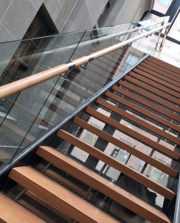 Glass staircase guardrail with wooden handrail
