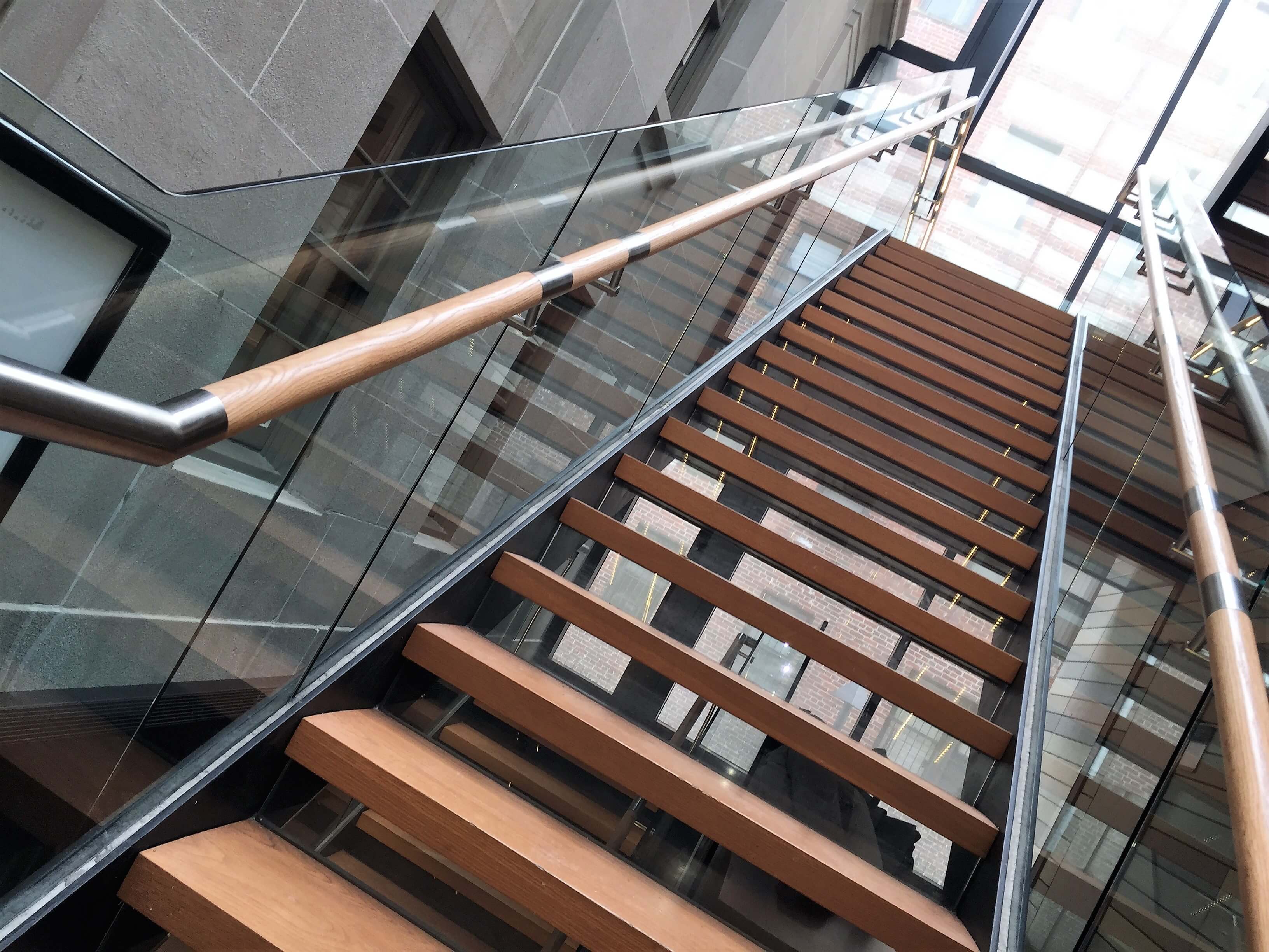 Glass staircase guardrail with wooden handrail